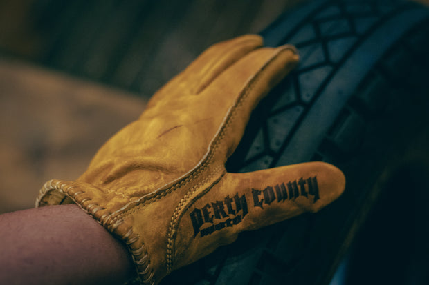 bronze-motostuka-motorcycle-gloves-with-perth-county-moto-branding-on-thumb
